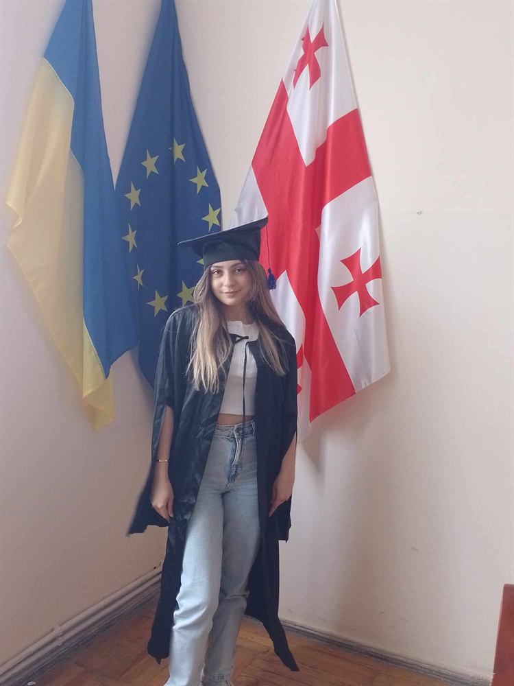 კურსდამთავრებული მანტიაში საქართველოს, ევროკავშირისა და უკრაინის დროშებთან